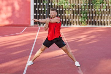 Spor sahasındaki spor salonunda kırmızı formalı bir sporcu.