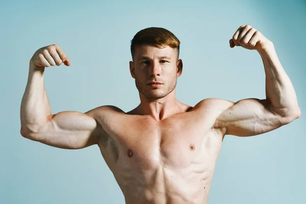 Fisiculturista com corpo muscular posando imprensa fundo azul — Fotografia de Stock