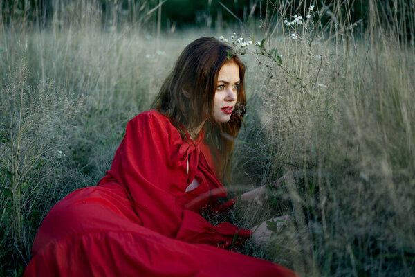 Woman in red dress lies on the grass nature freedom rest. High quality photo