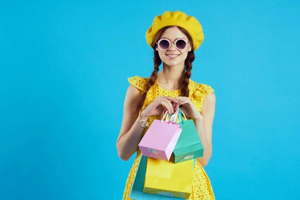 Wesoła kobieta żółty sukienka zakupy zabawa niebieski tło — Zdjęcie stockowe