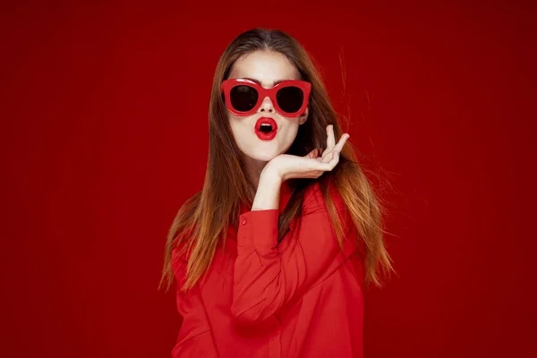 Приваблива жінка в сонцезахисних окулярах червоний фон — стокове фото