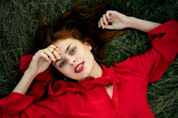 Mulher em vestido vermelho encontra-se na grama endereço moda verão — Fotografia de Stock