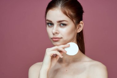 Çıplak omuzlu kadın pamuk pedleri saf ten cazibesi pembe arka plan