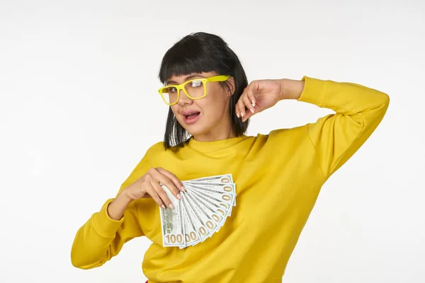 Kvinna i en gul tröja med pengar i händerna kul rikedom — Stockfoto