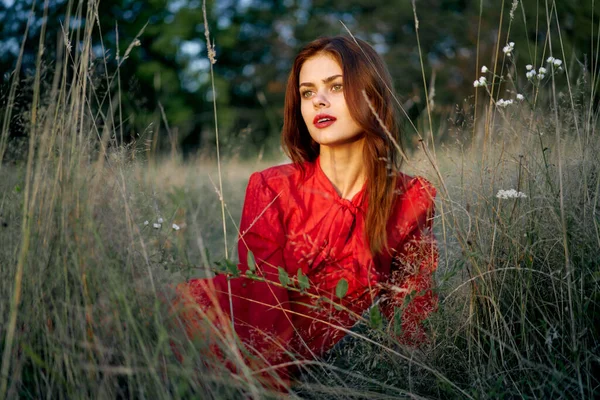 Femme dans une robe rouge se trouve sur l'herbe dans le domaine nature mode — Photo