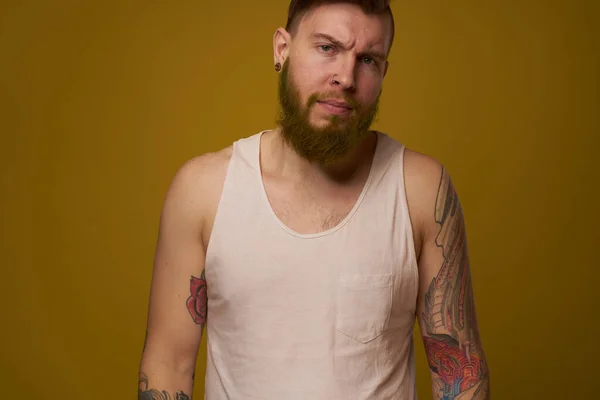 Vrolijke man met baard in een wit T-shirt met hooligan tatoeages op zijn armen — Stockfoto