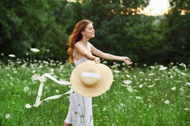 Beyaz şapkalı kadın elinde çiçekler, doğa yürüyüşü.