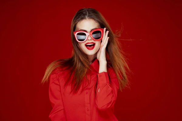 Приваблива жінка в сонцезахисних окулярах червоний фон — стокове фото