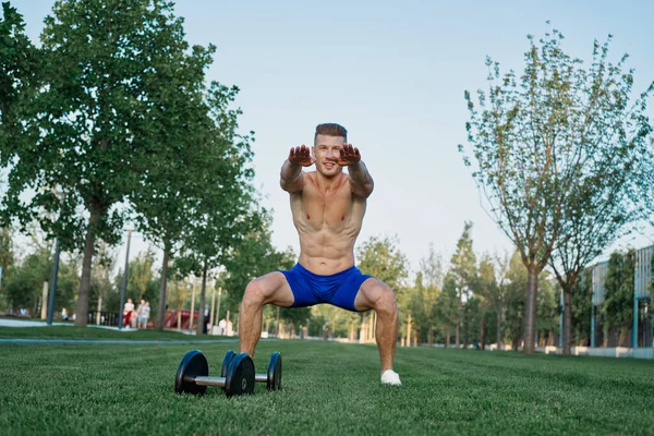Muscled man i parken träning med hantlar — Stockfoto