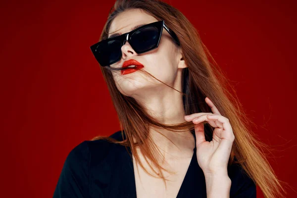 Alegre mujer de moda con gafas de sol labios rojos posando fondo rojo — Foto de Stock