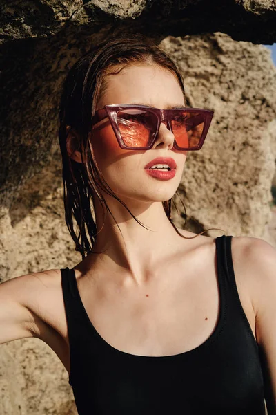 Woman wearing sunglasses swimsuit dispensing rocks travel — Stock Photo, Image