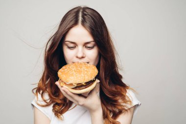 Elinde hamburger olan bir kadın. Atıştırmalık bir fast food.