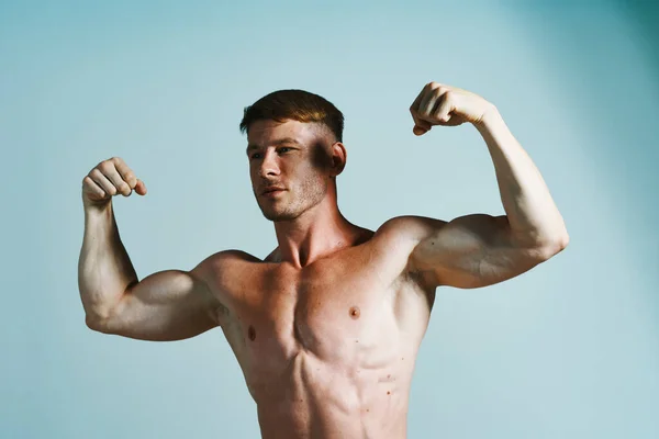 Bodybuilder med muskulös kropp poserar press blå bakgrund — Stockfoto