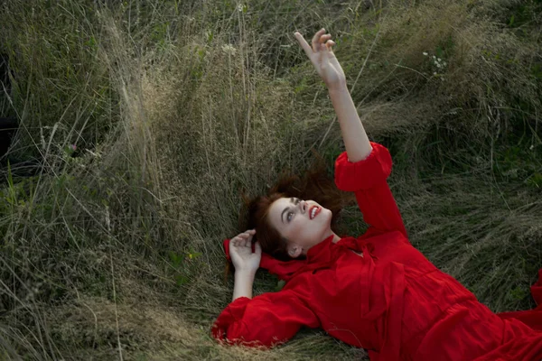 Femme en robe rouge se trouve sur l'herbe air frais nature liberté — Photo