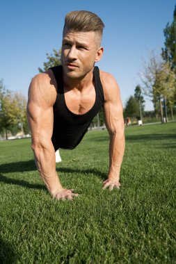 Parktaki spor salonunda vücudunu şişiren atletik adam. Temiz hava.
