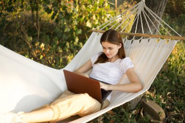 Kadınlar hamakta dizüstü bilgisayarlı tatil internetleriyle yatıyor.