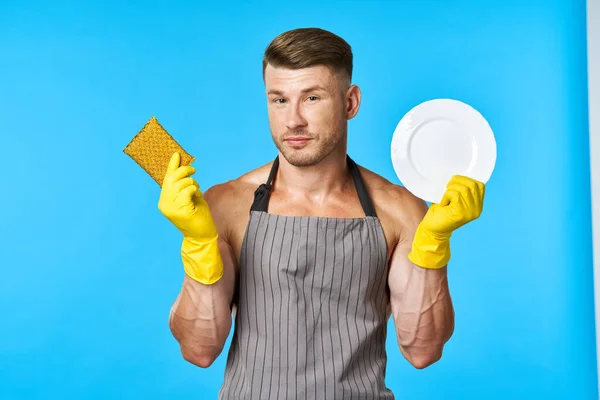 Man in schort reinigen vaatwassen blauwe achtergrond — Stockfoto