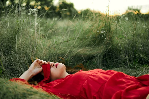 Woman in red dress lying on the grass fresh air nature romance — Stock Photo, Image