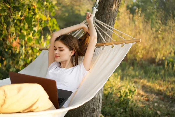 Vrouwen buiten ligt in een hangmat met een laptop freelance internet — Stockfoto