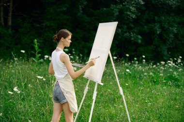 Resim paleti olan kadın ressam doğa hobisi çiziyor.