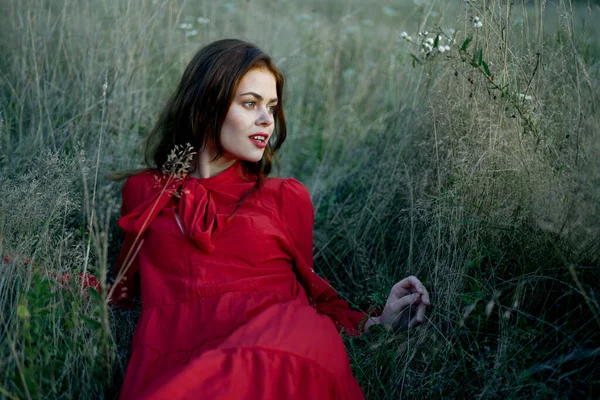 Woman lies on the grass in a red dress landscape fashion — Stock Photo, Image