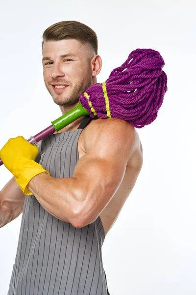 Homem muscular em um avental cinza com uma esfregona posando — Fotografia de Stock