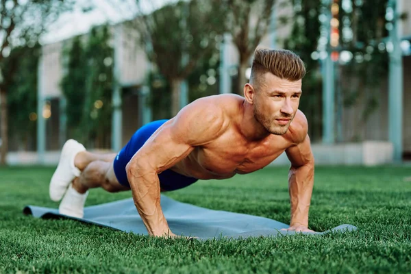 Parkta spor yapan kaslı vücutlu bir sporcu.