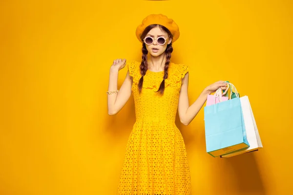 Veselá žena s pestrobarevné tašky pózovat žluté pozadí — Stock fotografie
