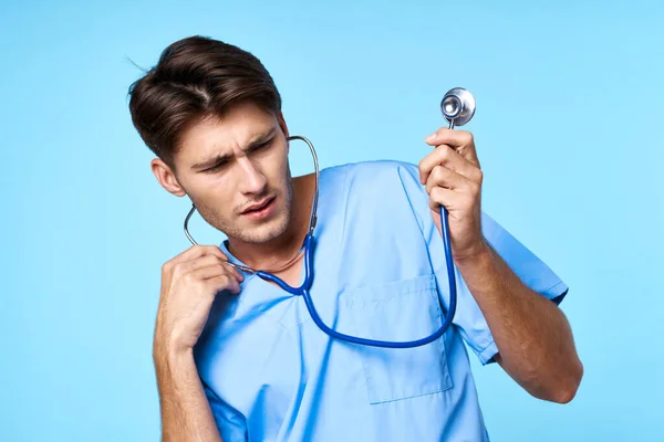 Uomo in uniforme medico trattamento sanitario stetoscopio esame sfondo blu — Foto Stock