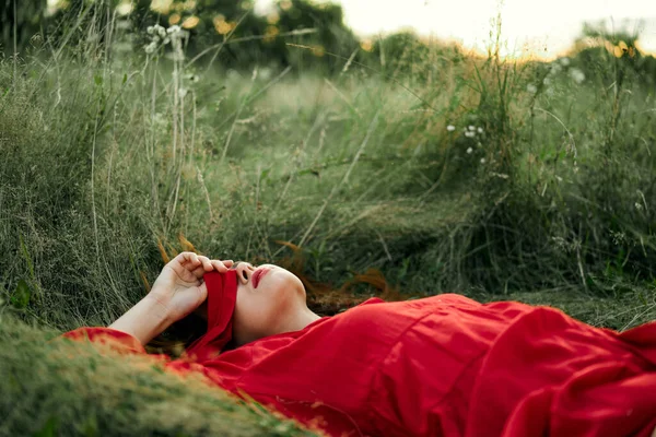Woman in red dress lying on the grass fresh air nature romance — Stock Photo, Image