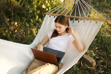 Kadınlar hamakta dizüstü bilgisayarlı tatil internetleriyle yatıyor.
