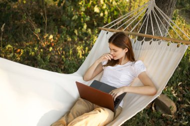 Kadınlar hamakta dizüstü bilgisayarlı tatil internetleriyle yatıyor.