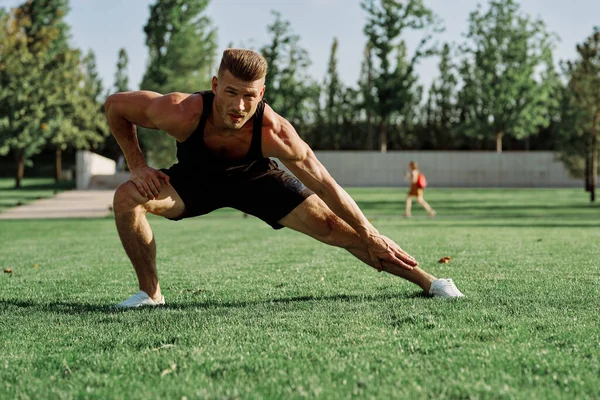Parktaki çimlerde egzersiz yapan sporcu.