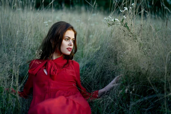 Donna in abito rosso si trova sull'erba natura libertà riposo — Foto Stock