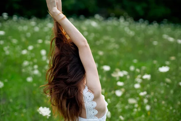 Mujer en vestido blanco en un campo de flores caminar libertad — Foto de Stock