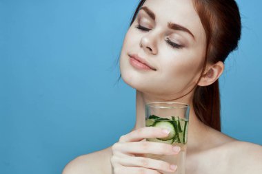 Salatalıklı güzel bir kadın sağlık vitaminleri içer.