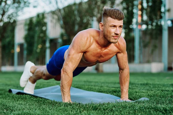 Parkta spor yapan kaslı vücutlu bir sporcu.