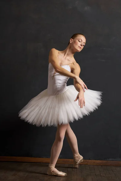 Mulher bailarina em um branco tutu dança posando desempenho fundo escuro — Fotografia de Stock