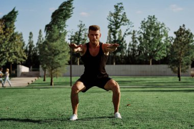 Parktaki çimlerde egzersiz yapan sporcu.