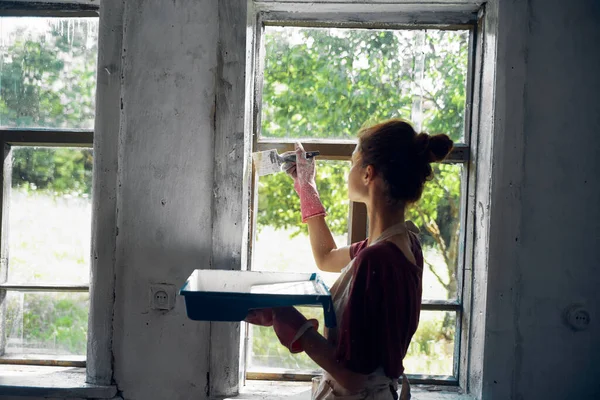 Женщина красит окна в интерьере дома ремонт комнаты — стоковое фото