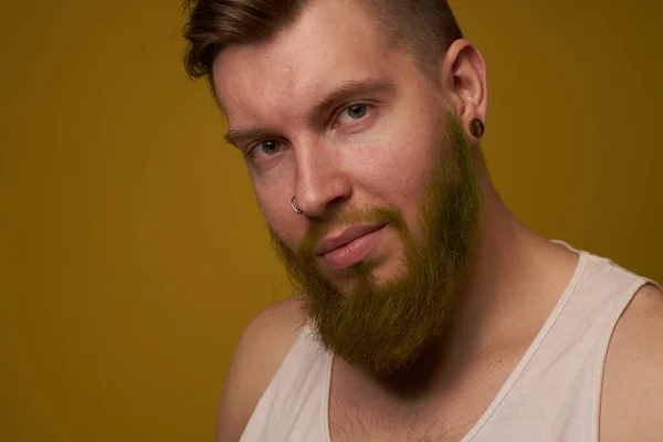 A bearded man with a serious expression in a white t-shirt with tattoos on his arms — Stock Photo, Image