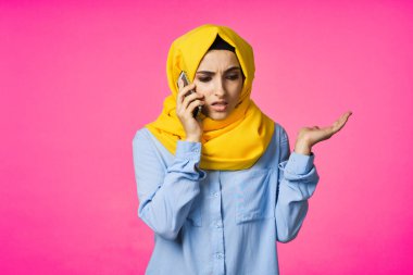 tesettürlü Müslüman kadın telefon iletişim teknolojisi pembe arka plan