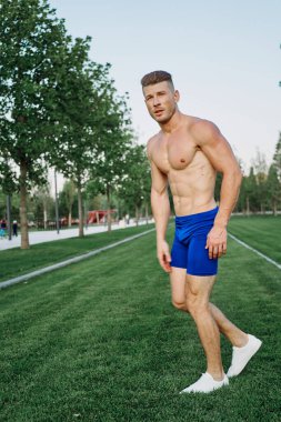 Parkta vücut egzersizi yapan atletik bir adam.