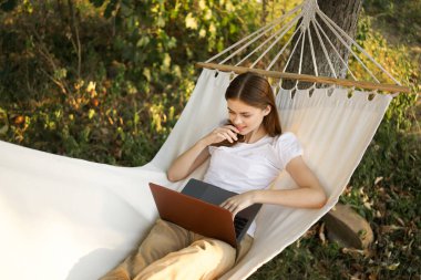 Kadınlar hamakta dizüstü bilgisayarlı tatil internetleriyle yatıyor.