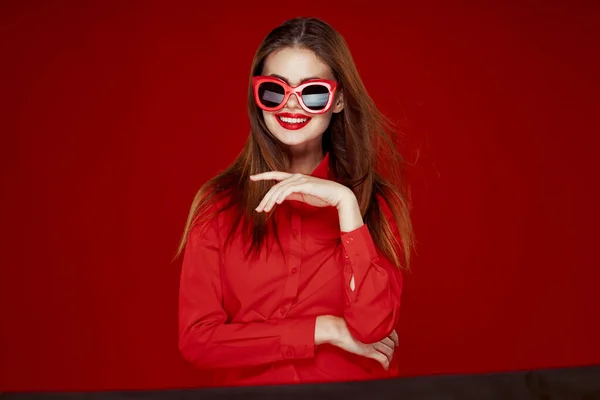 赤いシャツのサングラスファッションの魅力的な女性赤の背景 — ストック写真