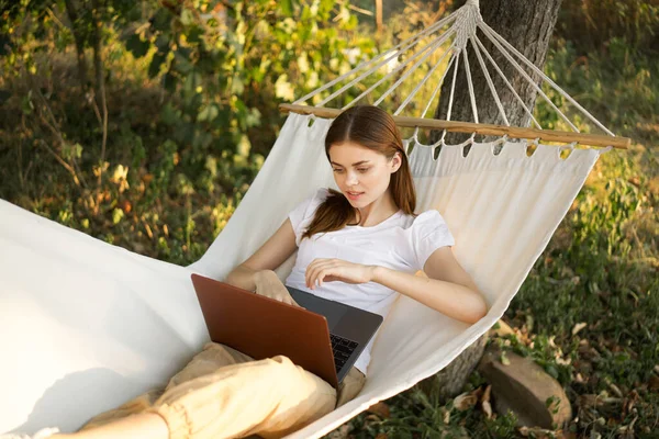 Kadınlar hamakta dizüstü bilgisayarlı tatil internetleriyle yatıyor.