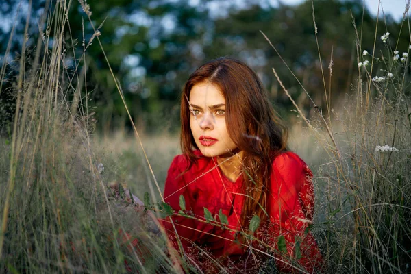 Kırmızı elbiseli kadın çimenlerin üzerinde uzanmış, doğa modasında. — Stok fotoğraf