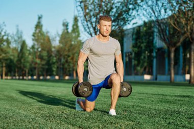 Atletik adam sabah halterlerle antrenman yapıyor. Park.