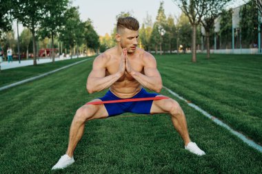 Atletik adam parkta koşma egzersizi yapıyor.