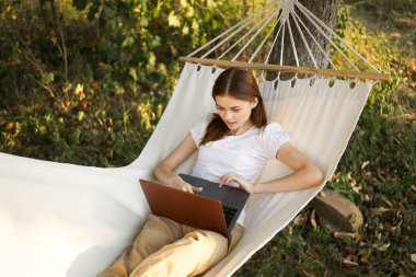 Kadınlar hamakta dizüstü bilgisayarlı tatil internetleriyle yatıyor.